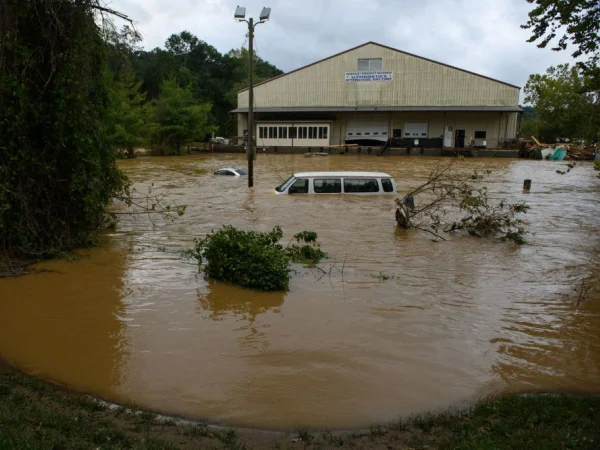 Foto colorida de carro e casa submersos em inundação - Metrópoles