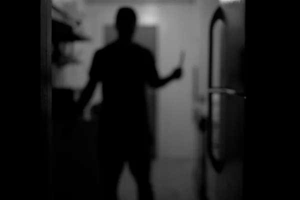 Imagem preta em branca da silhueta de um homem segurando uma faca - Metrópoles