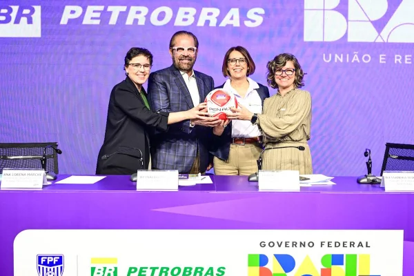 Quatro pessoas seguram uma bola em evento coorporativo da Petrobras. Entre elas está o presidente de Federação Paulista de Futebol, além de duas mulheres