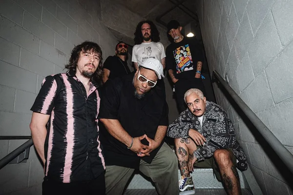 Foto do grupo Planet Hemp. Seis homens posam para uma foto em uma escada. Três estão em pé no fundo, um está sentado na escada e dois em pé na frente da imagem - Metrópoles