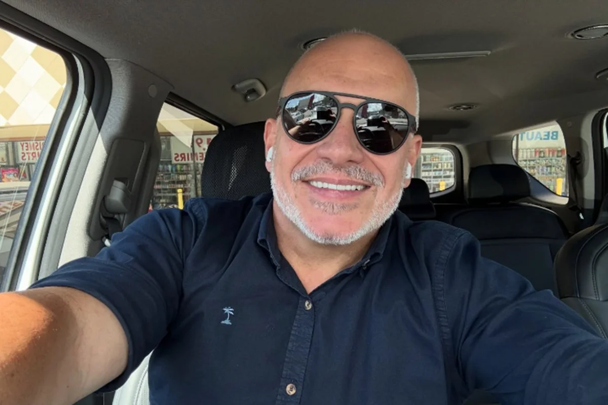 Imagem colorida do ator Sandro Rocha sorrindo e usando óculos - Metrópoles