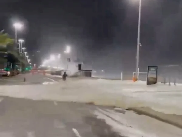 Foto colorida de ondas invadindo pista e derrubando ciclista - Metrópoles