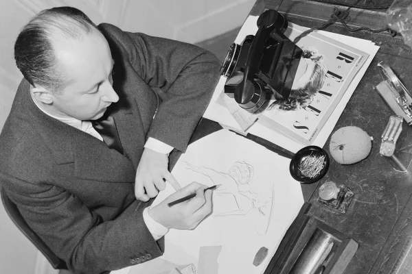 Estilista Christian Dior desenhando um croqui