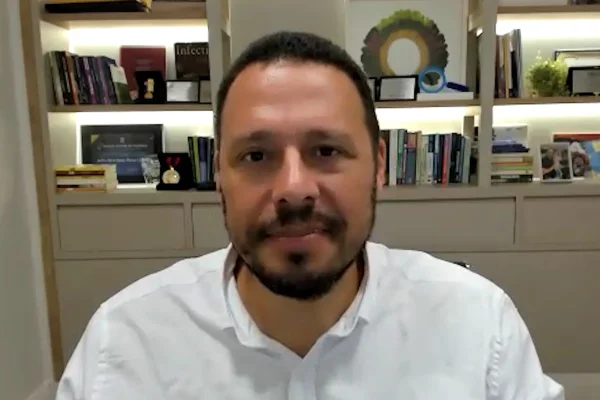 Homem de camisa branca em frente a uma estante - Metrópoles