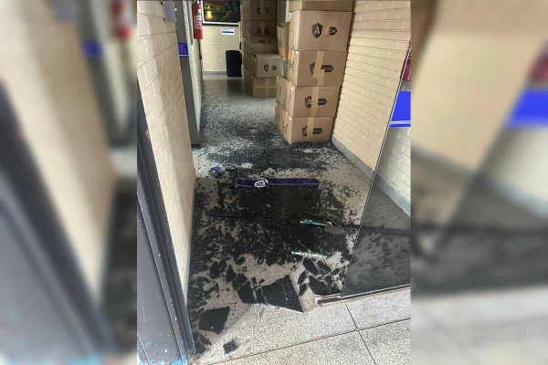 Porta de vidro preta quebrada com estilhaços no chão - Metrópoles