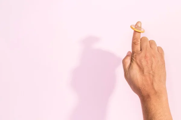 Mão com dedo levantado e um preservativo na ponta