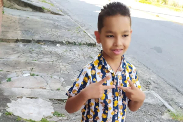 Imagens coloridas mostram menino de cabelos curtos, em pé, na calçada