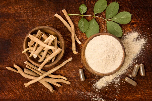 Pó de superalimento de Ashwagandha e raiz em tábua de corte sobre mesa de madeira vista de cima. Suplemento ginseng indiano
