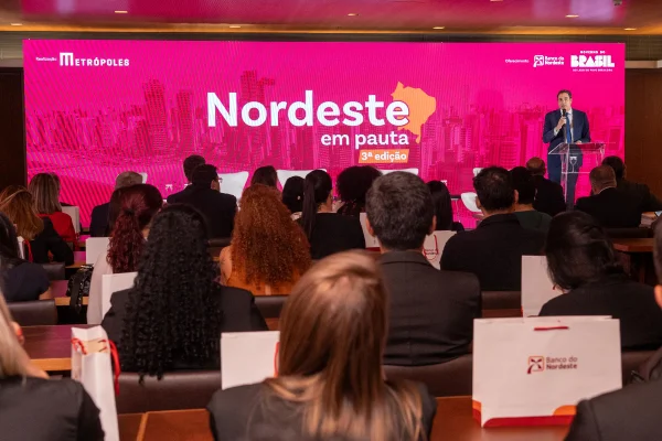 Fotografia colorida mostrando homem de terno discusando em palco-Metróples