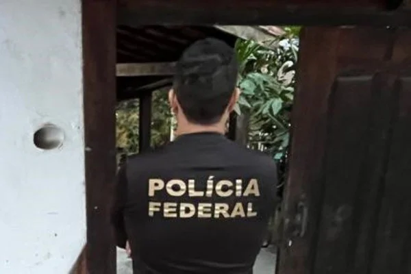 Imagem colorida mostra homem branco de cabelos curtos e escuros de costas. Ele veste uma camisa preta com os dizeres "Polícia Federal" nas costas - Metrópoles