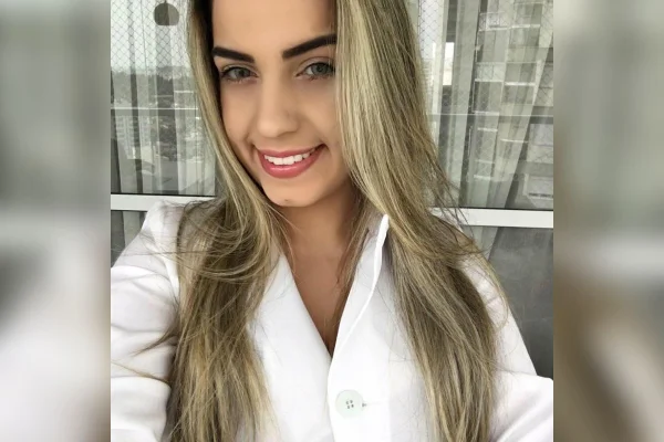 Imagem colorida mostra Natália Becker, mulher branca, loira, de olhos claros, usando jaleco branco, sorrindo para a câmera - Metrópoles