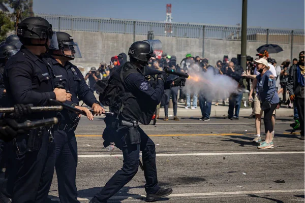 Foto colorida de manifestantes entrando em confronto com a polícia no centro de Los Angeles, perto do Prédio Federal e do Centro de Detenção Metropolitano, devido às operações de imigração que assolam Los Angeles - Metrópoles