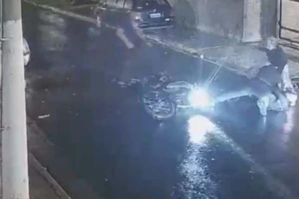 Imagem colorida mostra print de imagem de câmera de segurança com moto caída no chão de uma rua - Metrópoles