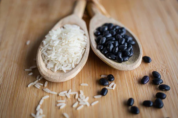 Foto colorida de colheres com arroz e feijão como opções de fibras