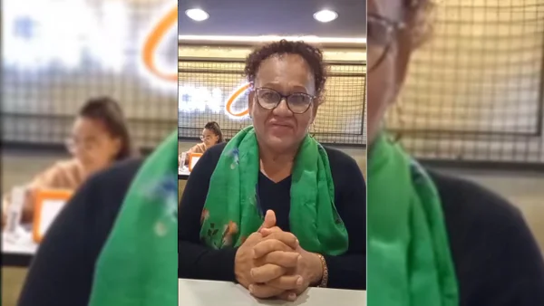 Mulher negra de blusa preta e cachecol verde