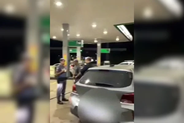 Imagem colorida de um carro prata parado com agentes da PM e um homem de pé ao redor - Metrópoles