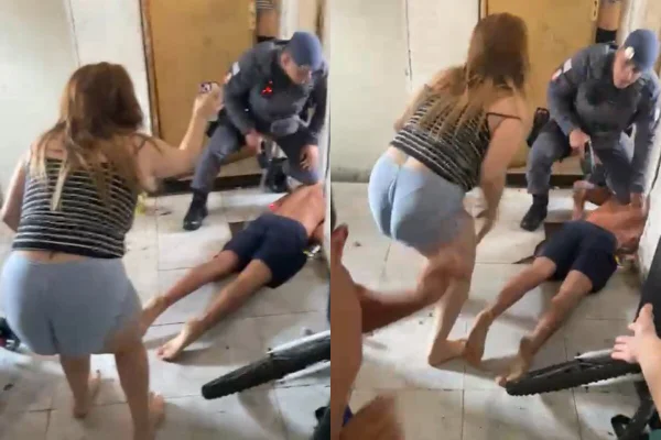 Policial mantém joelho sobre costa de homem, sem camiseta e bermuda escura, caído em chão branco - Metrópoles