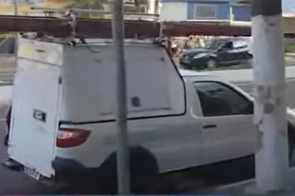 Imagem colorida de carro branco com escada de madeira em cima. na imagem também aparecem um poste e um mastro de placa. Um funcionário da Enel morreu no local após levar um tiro de um empresário - Metrópoles