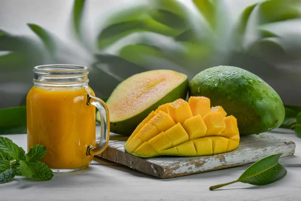 Foto de manga cortada em prato ao lado de copo com suco da fruta - Metrópoles