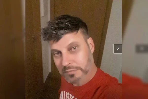 homem branco com barba rala e cabelo preto curto