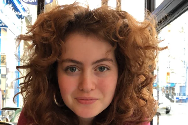 Foto colorida e com zoom, de mulher ruiva e olhos claros sorrindo para foto -Metrópoles