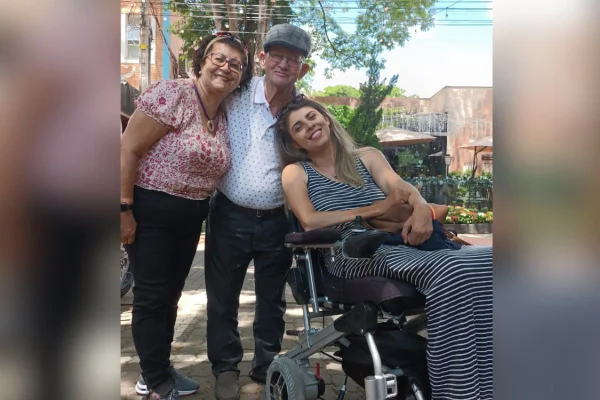 imagem colorida mostra três pessoas: uma mulher e um homem idosos, e uma mulher. a