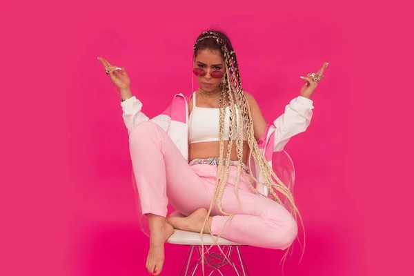 Flora Matos. Ela está de top branco e calça rosa claro. O fundo é rosa - Metrópoles