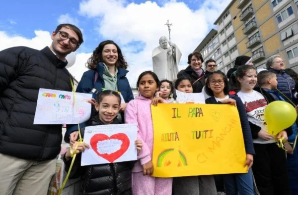 Foto colorida de crianças com desenhos e cartazes rezando pelo papa Francisco - Metrópoles