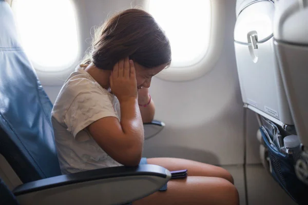 Foto colorida de uma criança na janela do avião - Metrópoles