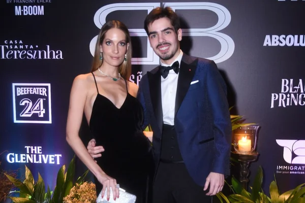 Schynaider Moura de vestido preto e João Guilherme Silva de terno - metrópoles