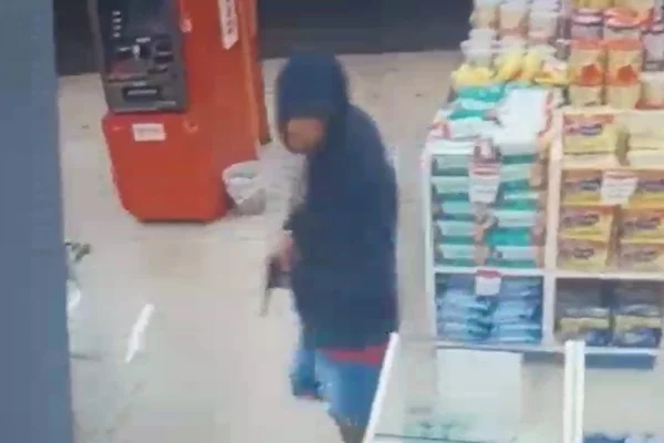 Homem com capuz e arma na mão em imagem de câmera de segurança