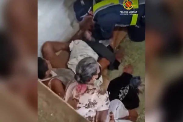 Agentes de segurança auxiliam mulher deitada no chão prestes a dar à luz uma criança