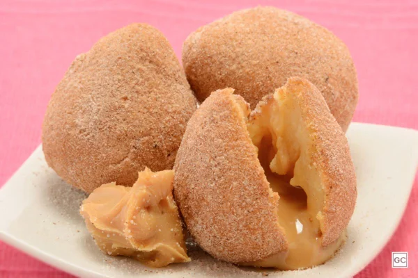 Coxinhas de churros, com doce de leite escorrendo de dentro de uma delas - Metrópoles