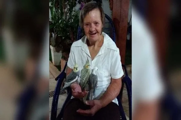 Imagem colorida, mulher , camisa branca, sorrindo com pássaros nos braços - Metrópoles
