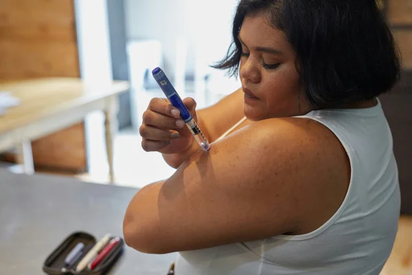 Foto colorida de mulher aplicando insulina no braço - Metrópoles.