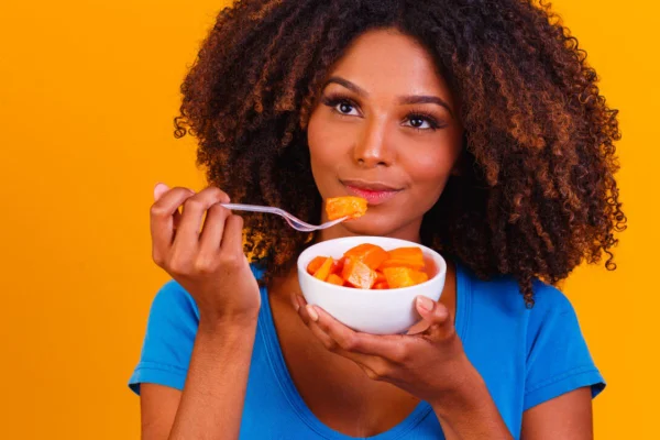 Foto de uma mulher negra comendo frutas