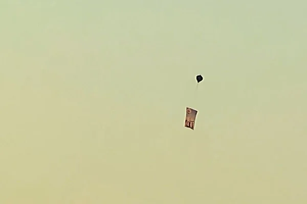 Imagem colorida de céu amanhecendo. É possível ver um balão com uma faixa pendurada abaixo - Metrópoles