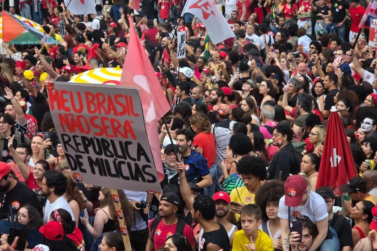 Apoiadores de Lula levam cartaz com referência à relação de Flávio Bolsonaro com milícias Apoiadores de Lula levam cartaz com referência à relação de Flávio Bolsonaro com milícias