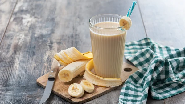 Foto colorida de copo contendo smoothie de banana sobre mesa