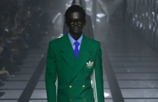 Na imagem com cor, modelo desfila com itens da parceria entre a Gucci e Adidas