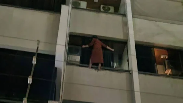 imagem colorida mulher pendurada janela pra fugir de ladrao goiania