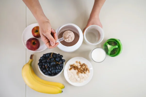 Imagem mostra suplemento whey protein com vários potes de frutas - Metrópoles