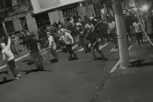 Imagem em preto e branco de torcedores das torcidas organizadas do Corinthians e São Paulo brigando - Metrópoles
