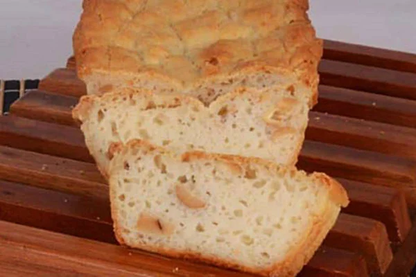 Na foto temos um pão com massa amarela sobre uma tabua de madeira