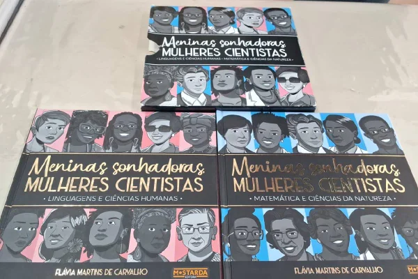 Três livros distribuídos sobre uma mesa de madeira- Metrópoles