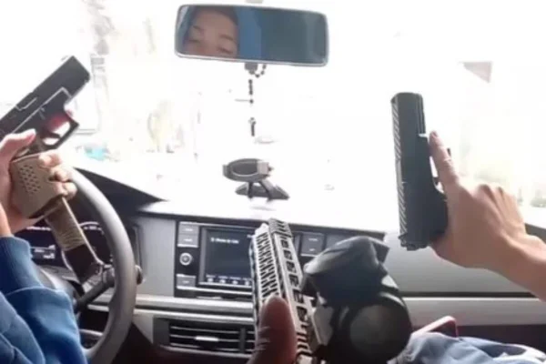 Foto colorida dentro de carro, na perspectiva do passageiro do banco traseiro com motorista e copiloto segurando pistolas - Metrópoles
