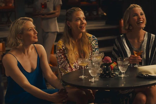 Imagem colorida de três mulheres sentadas em uma mesa