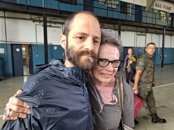 Foto colorida da aposentada Evelyn Crimerman e do filho Tiago Marchesano na base aérea de São Paulo, em Guarulhos, após retorno dela de Israel - Metrópoles