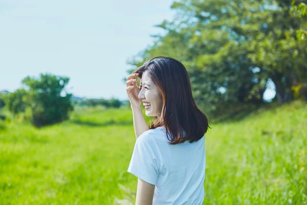 Foto colorida de uma mulher sorrindo no parque - Metrópoles