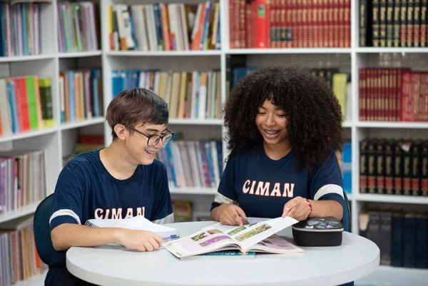 Fotografia colorida mostrando dois estudantes em biblioteca-Metrópoles